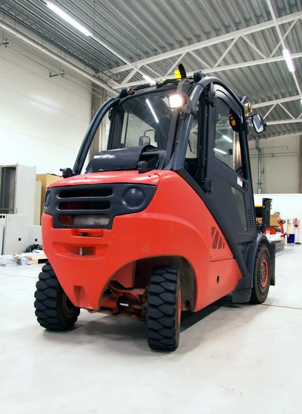 Orange forklift loader in the modern warehouse.