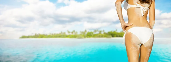 Young woman in bikini looking at island