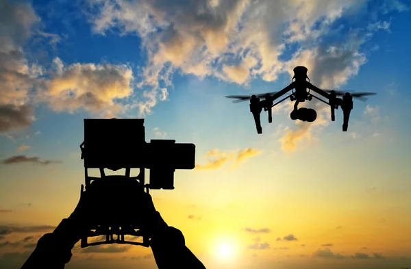 Man hands handling drone in sunset silhouettes