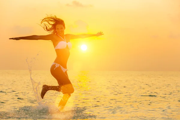 Girl jumping on the beach at sunset