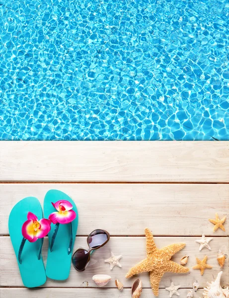 Beach accessories on wooden background with pool