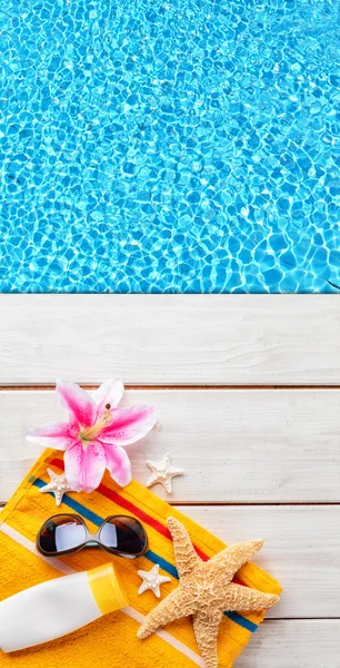 Beach accessories on wooden background with pool