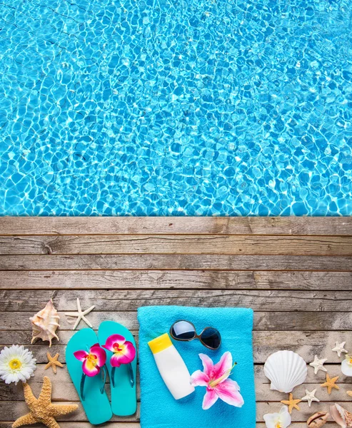 Beach accessories on wooden background with pool