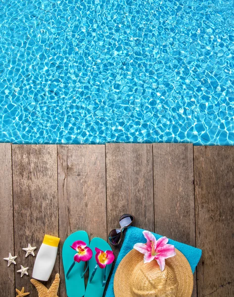 Beach accessories on wooden background with pool