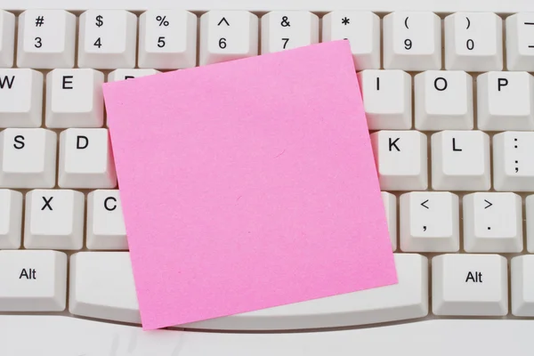 Computer Keyboard with a pink blank sticky note