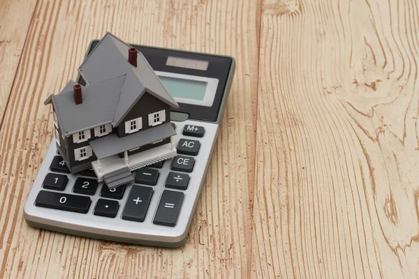 A gray house and calculator on wood background