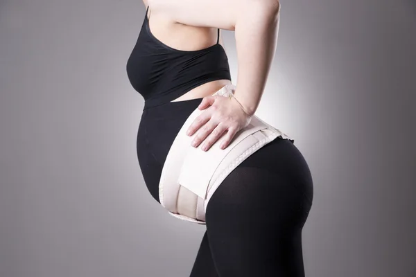 Young caucasian pregnant woman with orthopedic support belt