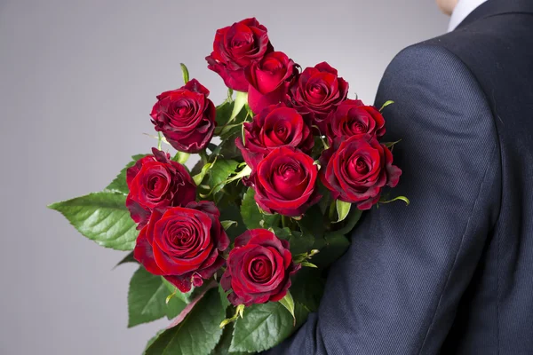 Man with bouquet of red roses on a gray background