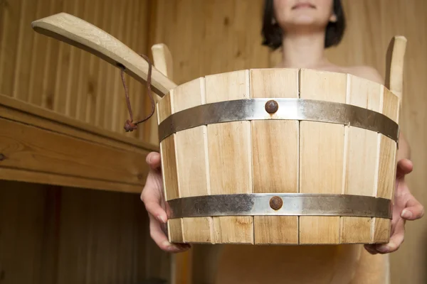 Bucket in the hands of women in sauna, bath accessories