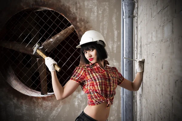 Beautiful young sexy woman in a white helmet posing with construction equipment