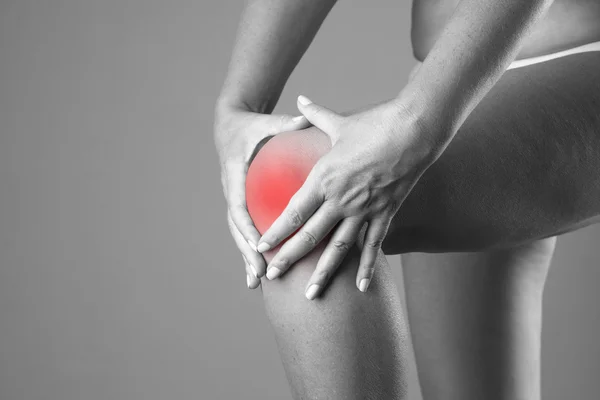 Pain in the knee. Pain in the human body on a gray background