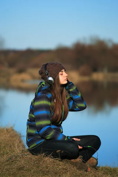 Young girl sitting on the ground  and listening  music after hik