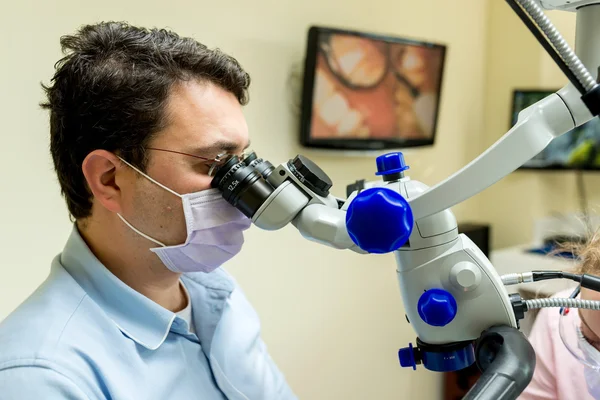 Dentist doing a dental treatment on a patient with microscope