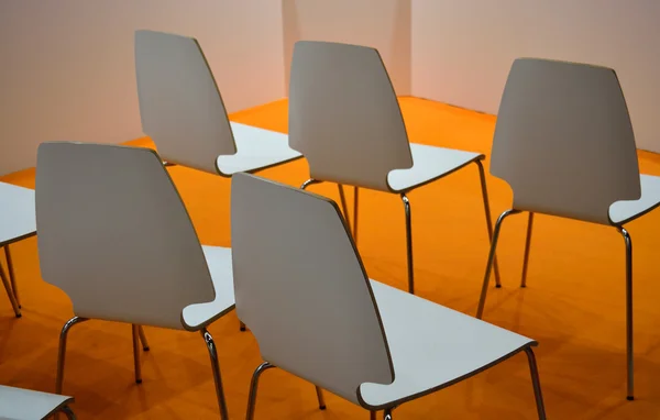 White plastic chairs over orange floor in a conference room