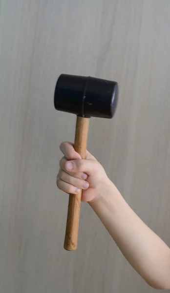 Child\'s fist with a black mallet a wooden handle