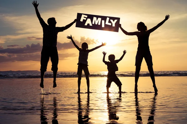 Happy family standing on the beach at the sunset time.