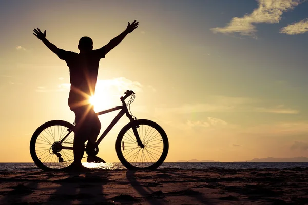 Happy man with bicycle standing on the beach