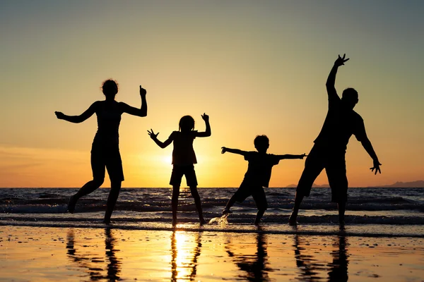 Silhouette of happy family who standing on the beach at the suns
