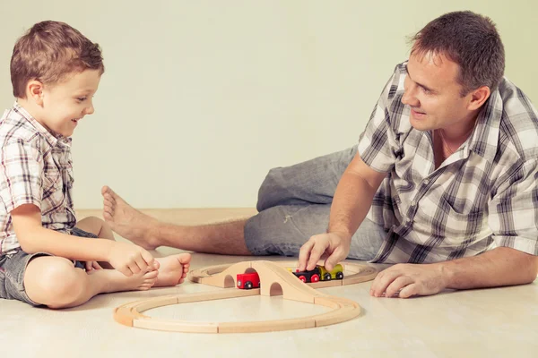 Daddy with little boy playing with toy train on the floor at the