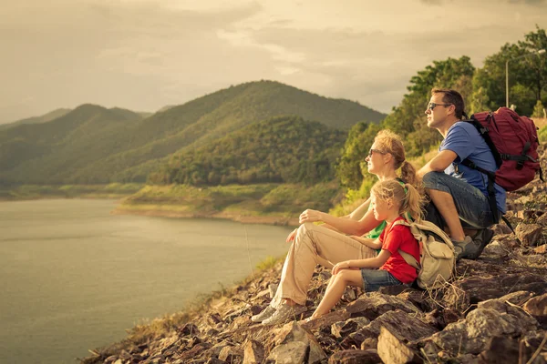 Happy family sitting near the lake at the day time.