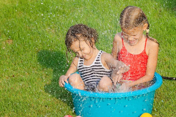 Brother and sister playing with water near a house