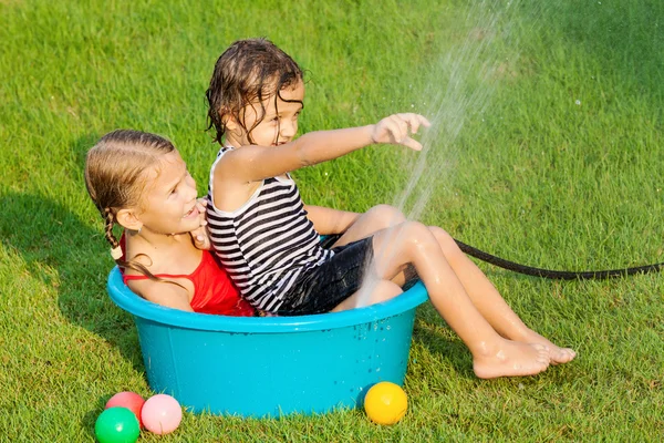 Brother and sister playing with water near a house