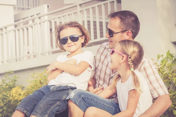 Dad and children playing near a house at the day time.