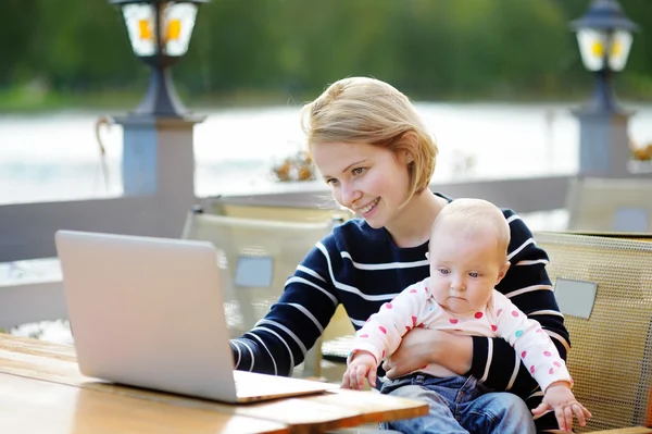 Young mother with her baby working or studying on her laptop