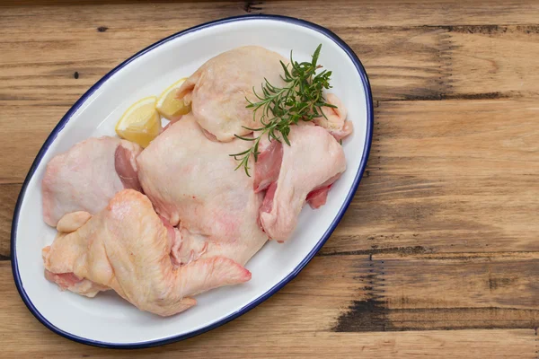 Raw chicken on dish on brown wooden background