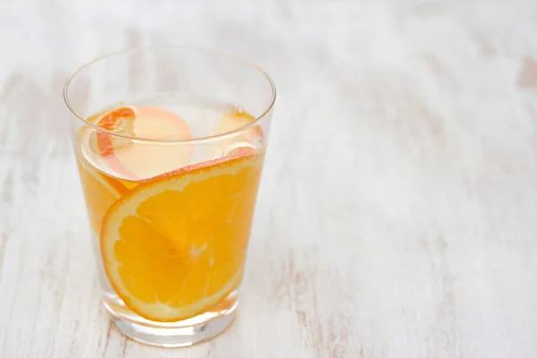 Orange drink in glass on white wooden background
