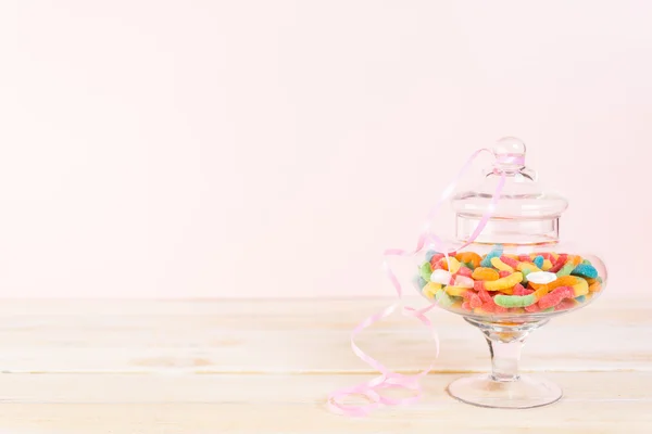 Candies in candy jar on wood table.