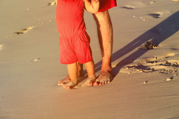 Close up of father and little daughter feet on beach