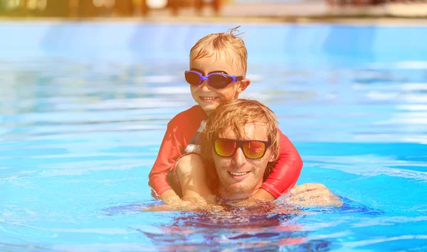 Happy father and son swimmimng in the pool