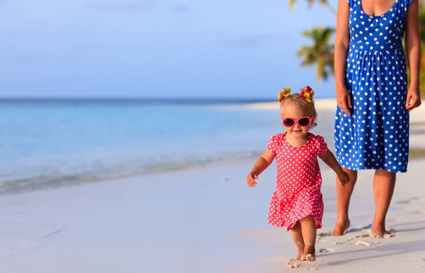 Cute little girl with mother running on the beach