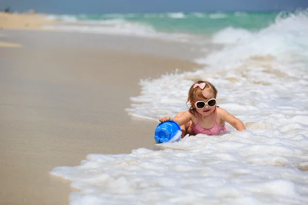 Cute little girl play with sand and water on beach