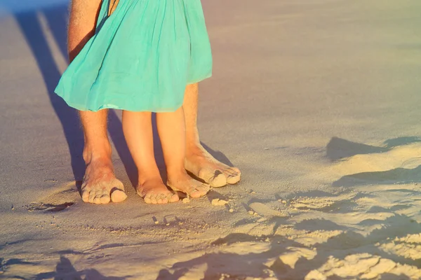 Close up of father and little daughter feet on beach