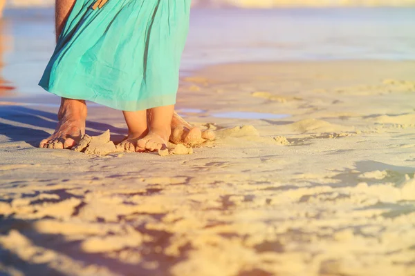 Close up of father and little daughter feet on beach