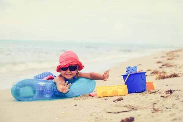 Little girl plays with sand on beach