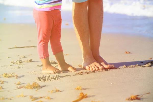 Father and little daughter feet on beach