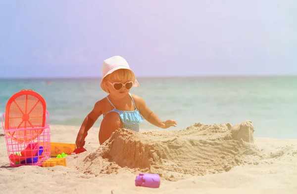 Girl plays with sand and toys on beach