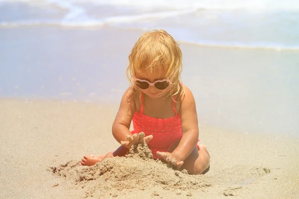 Girl plays with sand on beach