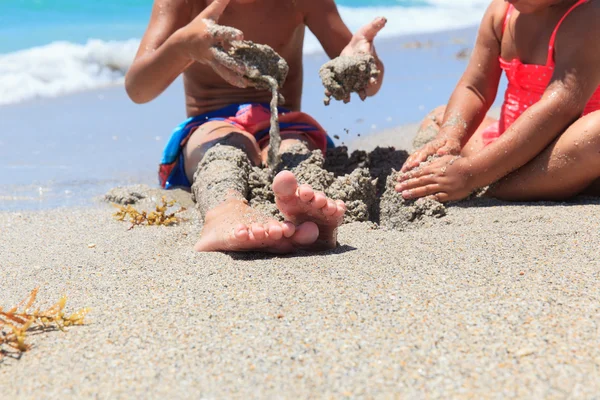 Boy and girl play with sand on beach