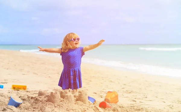 Girl plays with sand on beach