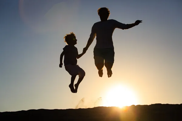 Father and son jumping at sunset
