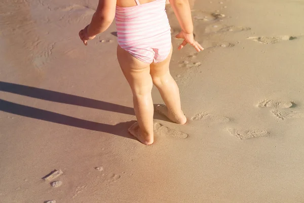 Little girl feet play on beach