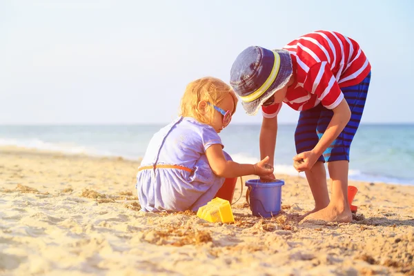 Kids play with sand on summer beach