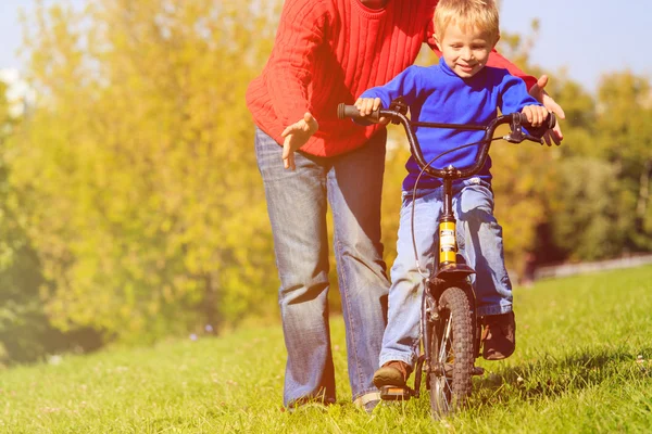 Father teaches son to ride bicycle