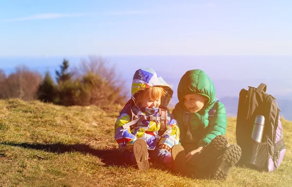 Little boy and girl with backpacks travel in mountains