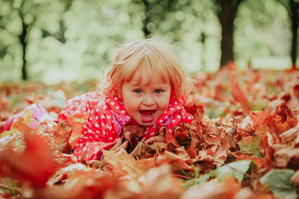 Cute little girl playing with autumn fall leaves