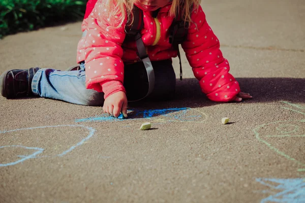 Little girl drawing on asphalt after school